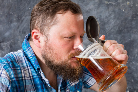 Matured smiling bearded man in shirt with beer mugの写真素材