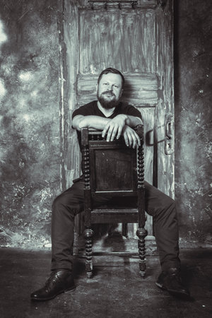 Mature bearded man sitting on vintage door backgroundの写真素材