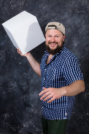 Joyful bearded man in shirt with blanc cube object for your logoの写真素材