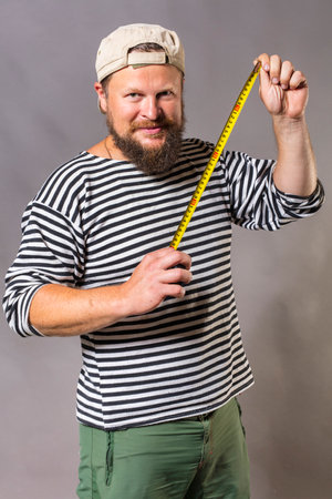Joyful bearded craftsman with tape measureの写真素材