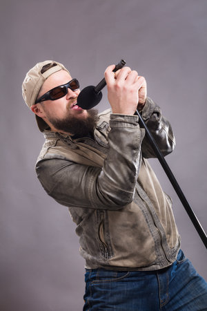 Bearded emotional rock singer with microphone studio portrait.の写真素材
