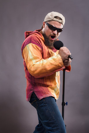 Bearded emotional rock singer with microphone studio portrait.の写真素材