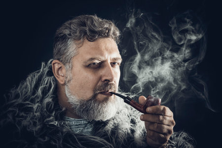 Solid bearded man in a fur mantle smoking pipeの写真素材