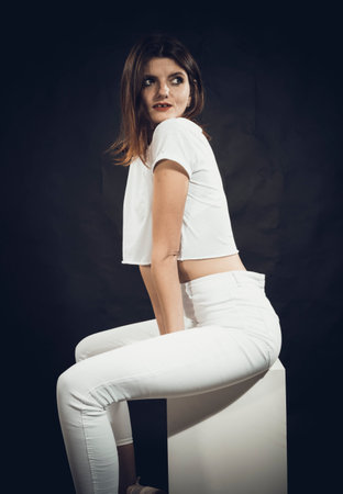 Studio portrait of young beautiful woman dressed in a white jeans and t-shirtの写真素材