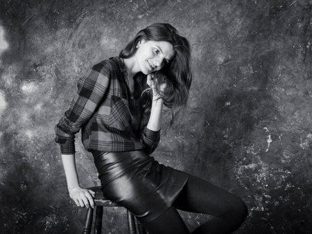 Studio portrait of young beautiful woman in a leather skirtの写真素材
