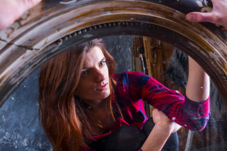 Young longhaired beautiful woman sitting in front of the vintage mirrorの写真素材