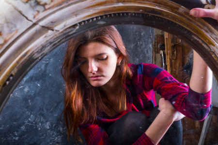 Young longhaired beautiful woman sitting in front of the vintage mirrorの写真素材
