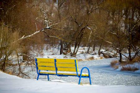 Beautiful winter landscape with frosen river and the bench snowy scene.の写真素材