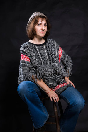 Cheerful 40 years old woman dressed in jeans and poncho studio portraitの写真素材