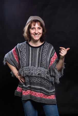 Cheerful 40 years old woman dressed in jeans and poncho studio portraitの写真素材