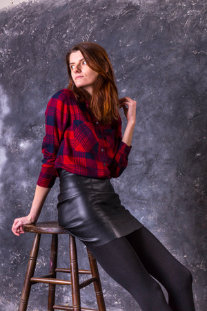 Studio portrait of young beautiful woman in a leather skirtの写真素材