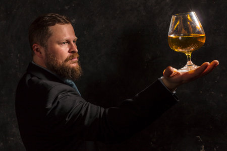 Solid confident bearded man in suit with glass of whiskyの写真素材
