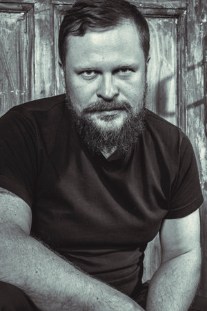 Mature bearded man sitting on vintage door backgroundの写真素材