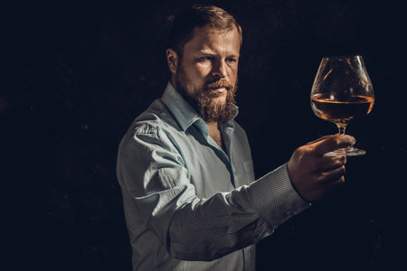 Solid bearded man in shirt with glass of whisky