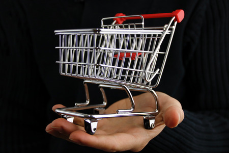 The shopping cart in male hands isolated on black backgroundの写真素材