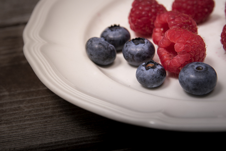 A mixture of raspberries and blueberries on white plateの写真素材