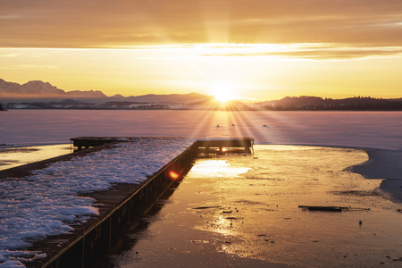 romantic sunset over a frozen lake, with wooden pier, wallersee, austriaの写真素材