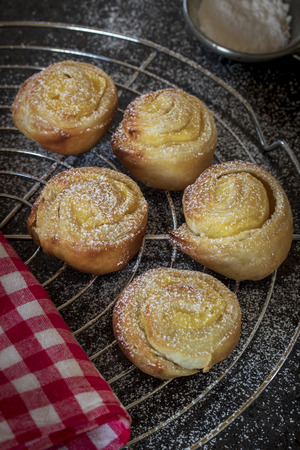 Small Vanilla snails with puff pastry on a cake rack, dark backgroundの写真素材