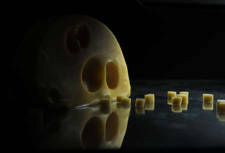 Pieces of swiss cheese on black backgroundの写真素材