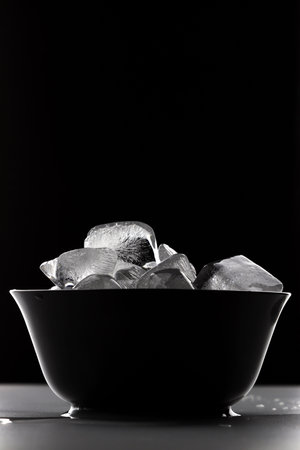 Black bowl filled to the brim with ice cubesの写真素材