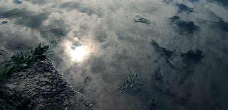 The Mysterious Shore. Reflection of cloudy sky in the river. low key.