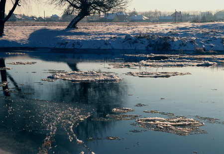 Winter landscape. Snow-covered shoreline with reflection of trees in the river. The state of solitude and unity with nature.の写真素材