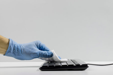 Side View Hand With Surgical Glove Disinfecting Keyboard With Copy Spaceの写真素材
