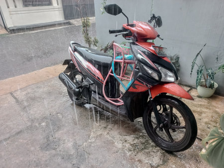 a motorbike left exposed to rain in the parking lotの写真素材