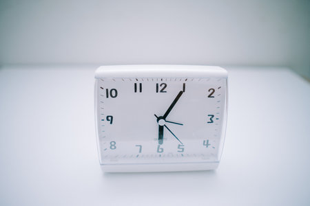 The work desk clock is placed on a white base in the form of a rectangular box. The clock shows 06:05 WIB,の写真素材