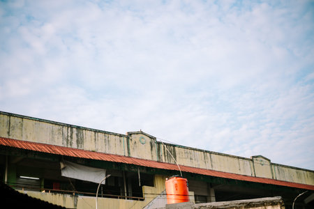 Amidst a vibrant sky, stands a weathered traditional market building, its aged facade echoing stories of bygone eras against the backdrop of a bright, hopeful skyの写真素材