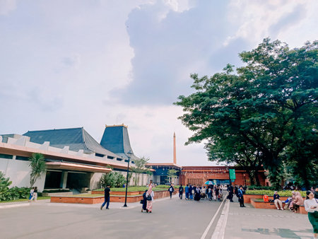 Jakarta, April 30 2024. A vibrant cityscape framed by a majestic tree against a clear blue sky, capturing the harmony between urban architecture and nature's beautyのeditorial素材