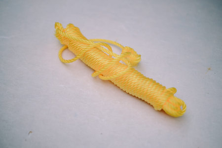 A coiled yellow rope, a symbol of readiness and safety in various settings such as sports,...