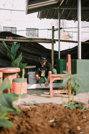 Bogor, Juni 17 2024. A man cuts wooden blocks to prepare a base for slaughtering sacrificial animalsのeditorial素材