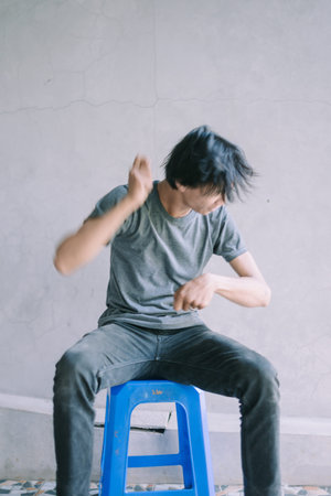 A Southeast Asian man expressing enthusiasm while playing an invisible drum, capturing a moment of imaginative performance, perfect for music, lifestyle, and creative projectsの写真素材