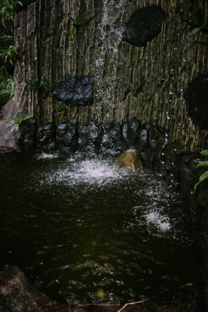 Artificial fish pond designed as a waterfall, capturing the beauty of flowing water and serene landscape, perfect for garden, nature, and outdoor projectsの写真素材