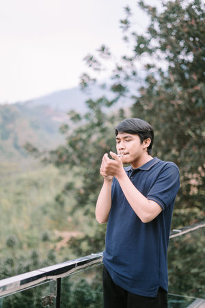 A Southeast Asian man, captured in a relaxed moment, with subtle details of the smoke visible