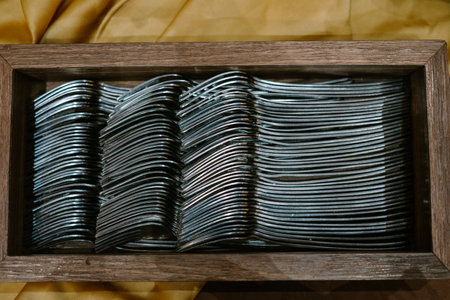 Dozens of silver forks neatly arranged in a rustic wooden holder, ready for dining or display.の写真素材