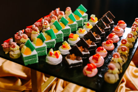 Hundreds of colorful, cute-shaped sweet pastries displayed on a table, ready to be served to guests.の写真素材