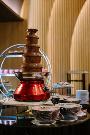 flowing chocolate fountain, rich and smooth, perfect for dessert buffets or special occasions, with layers of melted chocolate cascading down.の写真素材
