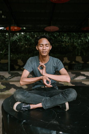 A Southeast Asian man meditating in a peaceful, contemplative pose.の写真素材