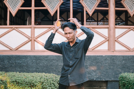 Southeast Asian man combing his hair, grooming himself in a well-lit settingの写真素材