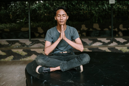 A Southeast Asian man meditating in a peaceful, contemplative pose.の写真素材