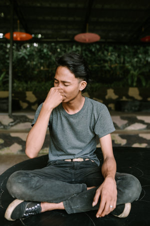 A Southeast Asian man holding his nose, possibly reacting to a smell or discomfort.の写真素材