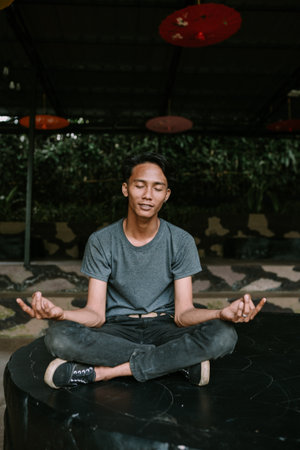 A Southeast Asian man meditating in a peaceful, contemplative pose.の写真素材