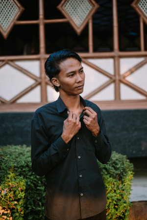 A Southeast Asian man wearing a black shirt poses stylishly in front of the camera.の写真素材