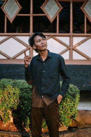 Southeast Asian man gesturing upwards, signifying a new idea or inspiration. Perfect for creativity, innovation, or problem-solving conceptsの写真素材