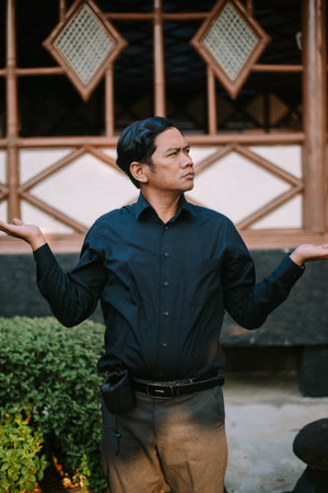 Southeast Asian man asking a question with a curious expression and engaged body language. Ideal for themes of inquiry, communication, or seeking informationの写真素材