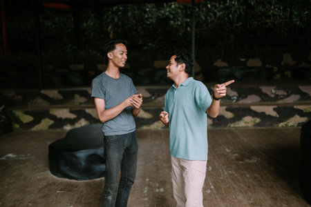 Two men standing and interacting in an outdoor setting, conveying a relaxed and friendly atmosphere.の写真素材