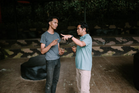 Two men standing and talking in an outdoor setting with a relaxed atmosphere.の写真素材