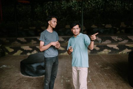 Two men standing in an outdoor area, one pointing towards something.の写真素材